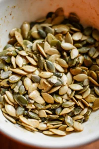 Combine pumpkin seeds with olive oil and seasonings