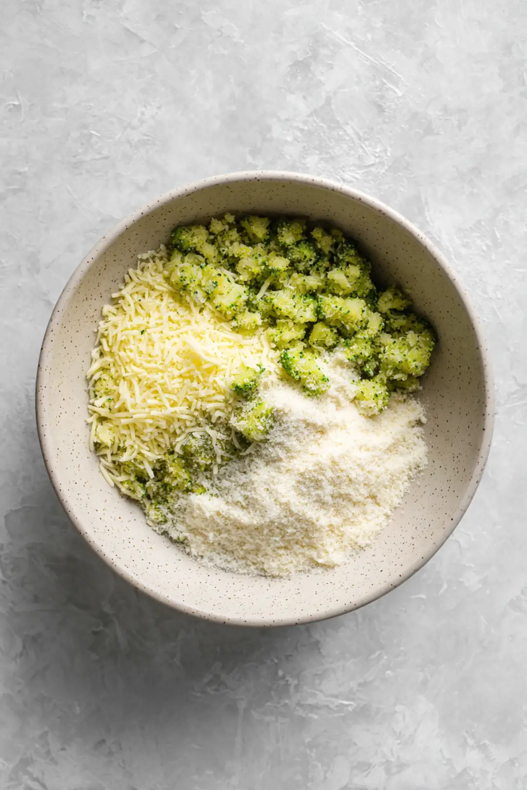 Combine shredded cheese, egg, bread crumbs, garlic powder, onion powder, salt, and pepper with chopped broccoli