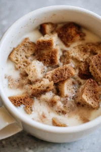 Combine torn bread pieces with egg, milk, sugar, vanilla extract, and cinnamon in a mug