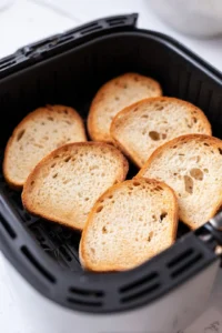 Cut a hole in the center of each slice of bread and place them in the air fryer basket.