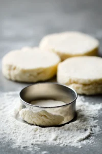 Cut each biscuit into a donut shape using a small round cutter or a knife.