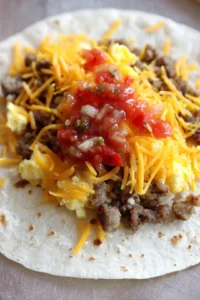 Layer cooked sausage, scrambled eggs, cheese, and salsa on tortillas and roll them up