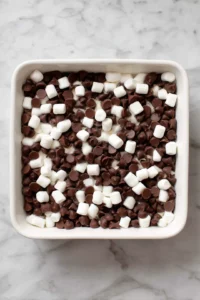 Layer semisweet chocolate chips and mini marshmallows in a small baking dish