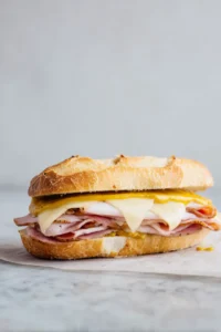 Layer Swiss cheese, roast pork, and ham in Cuban bread