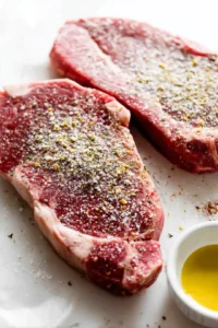 Lightly coat the ribeye steaks with olive oil and season generously with garlic powder, salt, and black pepper