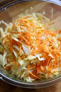 Mix shredded cabbage, carrot, lime juice, and salt to make slaw