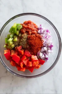 Mix the onion, garlic, bell pepper, olive oil, crushed tomatoes, smoked paprika, and cumin in a bowl