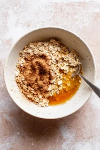 Mix together rolled oats, cinnamon, melted butter, and maple syrup until combined