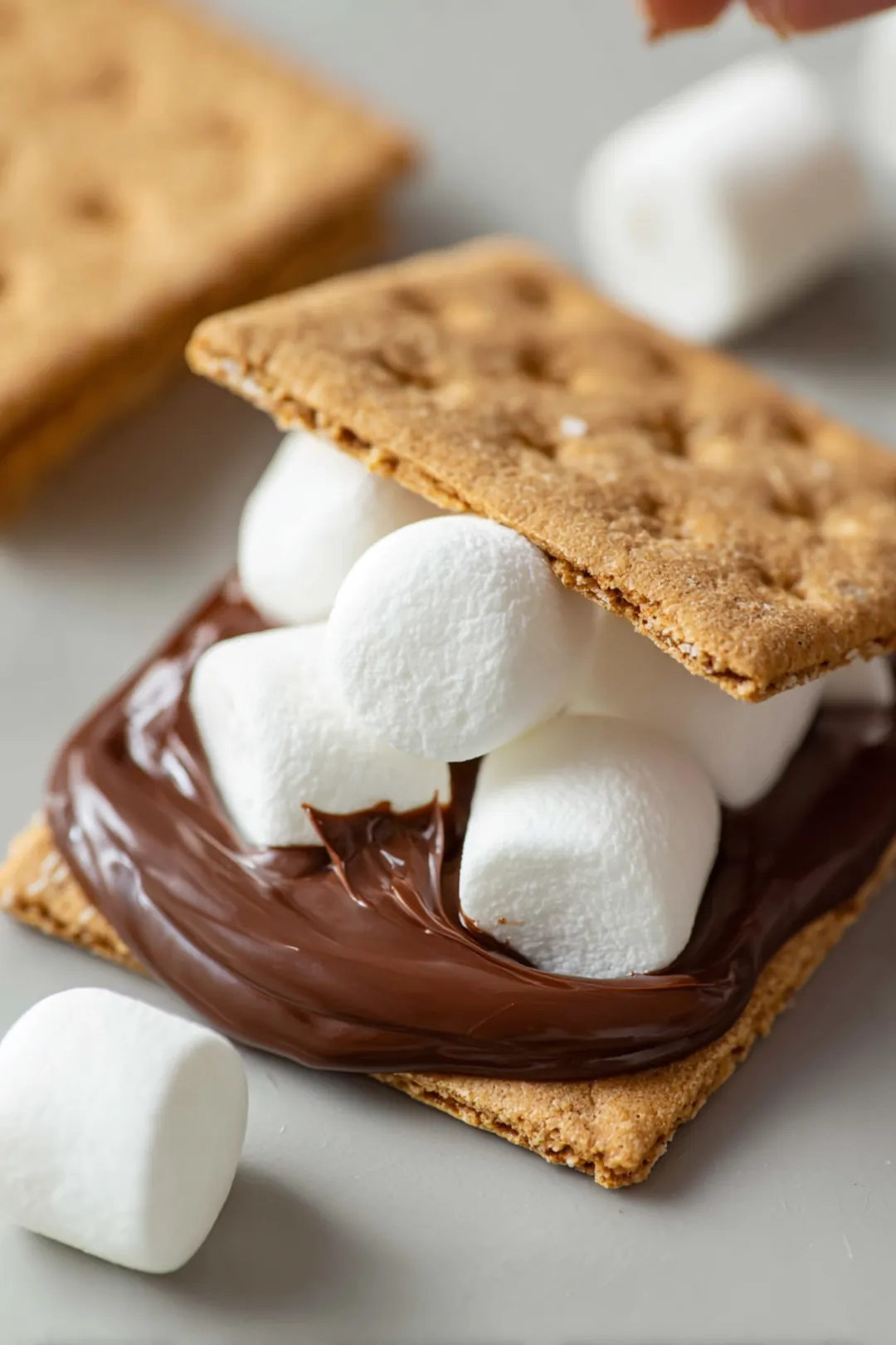 Place marshmallows on top of the chocolate spread, then close each s'more with a second graham cracker half.