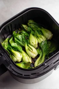Place the marinated bok choy in the air fryer basket and cook at 375°F (190°C) for 10-15 minutes, or until the edges are crispy and golden brown. Serve hot!