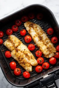 Place the seasoned cod and cherry tomatoes in the air fryer basket in a single layer