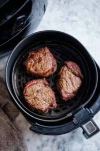 Place the steaks in the air fryer and cook until a nice crust forms.