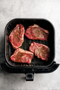 Preheat air fryer to 400 degrees Fahrenheit and season ribeye steaks