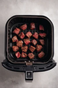 Preheat the air fryer to 400 degrees Fahrenheit and place the marinated steak bites in a single layer