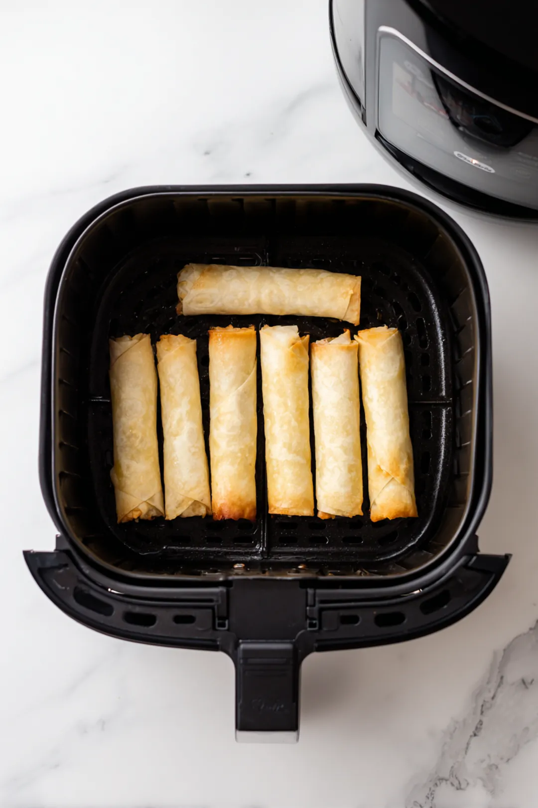 Preheat your air fryer and cook the spring rolls