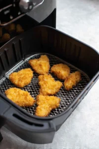 Preheat your air fryer to 390°F (200°C) and place the breaded chicken in the air fryer basket