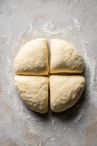 Shape dough into bagels by dividing into portions and poking a hole in the center