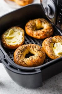 Spread a thin layer of butter on the cut sides of the bagels and place them cut-side up in the air fryer basket.