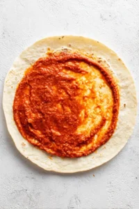 Spread a thin layer of pizza sauce over each tortilla