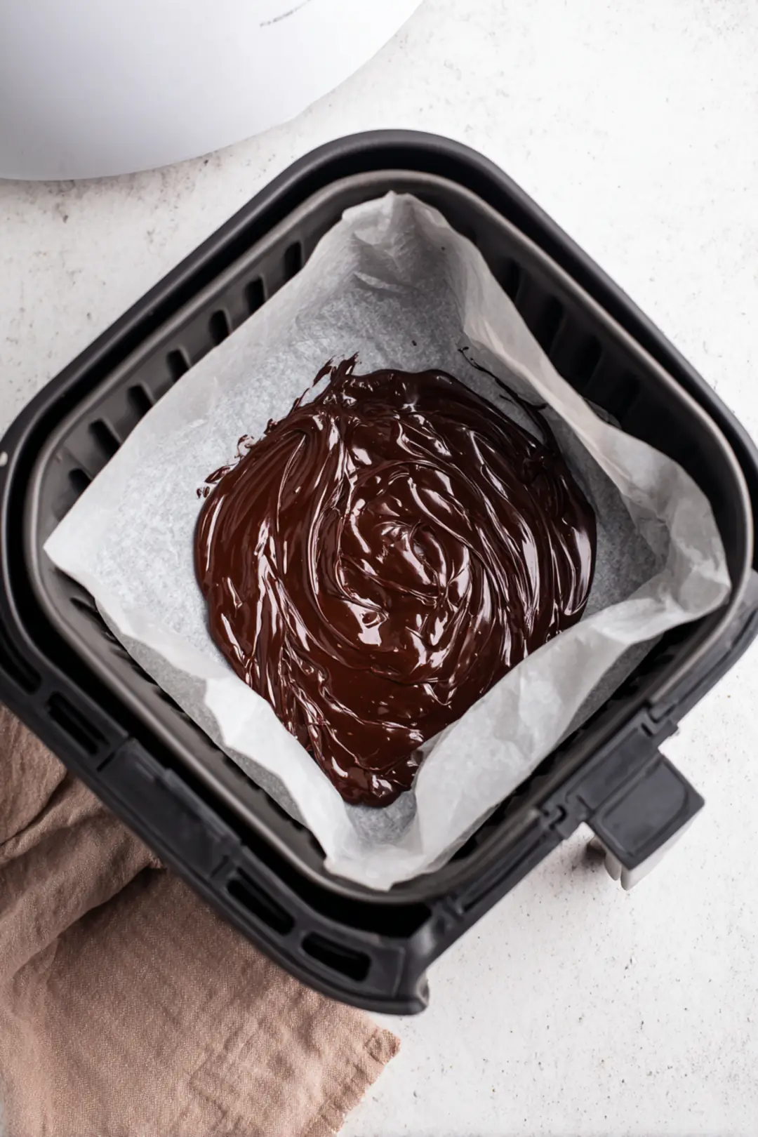 Spread the melted dark chocolate evenly in the bottom of a parchment-lined air fryer basket, and let it set for 5 minutes in the fridge.