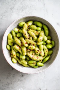 Toss frozen edamame with olive oil, sea salt, garlic powder, and red pepper flakes