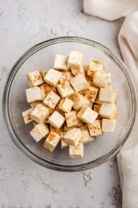 Toss pressed tofu cubes with olive oil, soy sauce, garlic powder, and ginger powder