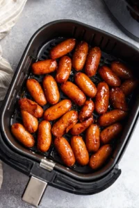 Toss the cocktail sausages in the glaze until fully coated and place them in the air fryer basket in a single layer.