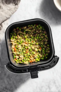 Transfer the edamame mixture to the air fryer basket and cook for about 10 minutes shaking halfway through until heated through and slightly crispy