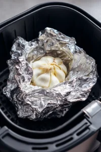 Wrap garlic head in aluminum foil and place in air fryer basket then cook for 20 minutes until cloves are soft and golden brown