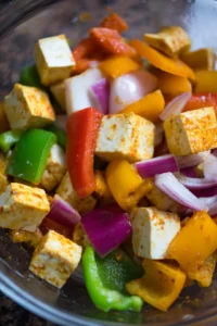 Add cubed paneer, bell pepper, and onion to the marinade