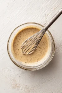 Add dijon mustard, salt, and black pepper to the mixture and whisk until smooth and creamy