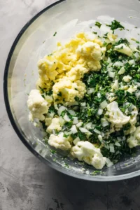 Add finely chopped spinach, cauliflower, and onion to the batter and mix until all vegetables are evenly coated