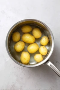 Boil halved baby potatoes in water until fork-tender