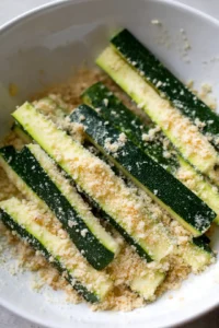 Coat zucchini strips in cheese mixture