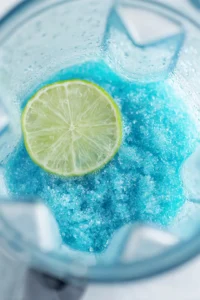 Combine blue curaçao, vodka, and fresh lime juice in a blender and blend until well mixed