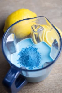 Combine blue spirulina powder, fresh lemon juice, agave syrup, and lukewarm water in a blender and blend until smooth.