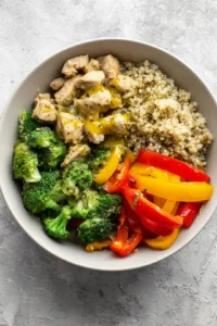 Combine chopped broccoli, sliced bell peppers, cooked quinoa, and chopped chicken in a mixing bowl