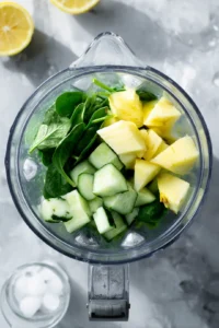 Combine chopped cucumbers, pineapple, fresh spinach, peeled ginger, and lemon juice with ice in a blender