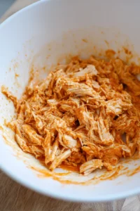 Combine cooked shredded chicken with buffalo sauce