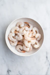 Combine flour, cornstarch, garlic powder, salt, and black pepper in a bowl, then toss shrimp until coated.