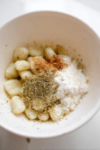 Combine gnocchi with olive oil, salt, pepper, garlic powder, and Italian seasoning