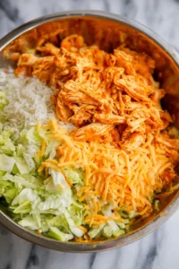 Combine shredded chicken with buffalo sauce, rice, cheese, and lettuce