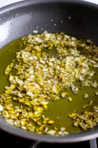 Heat olive oil in a large pan over medium heat and sauté chopped onions and minced garlic until softened and fragrant.