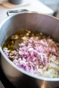 Heat olive oil in a large pot and sauté chopped onion and sliced leeks until softened