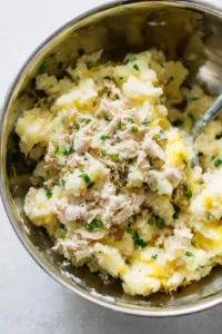Mash the potatoes and mix in the flaked tuna, egg, green onions, parsley, salt, and pepper until evenly combined