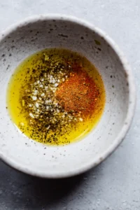 Mix olive oil, salt, garlic powder, paprika, and black pepper in a bowl to create a seasoning blend
