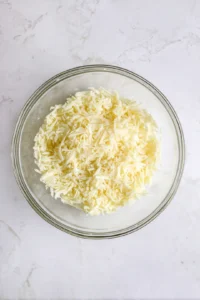 Mix shredded cheese, minced garlic, and olive oil in a bowl.
