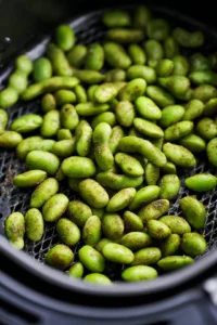Place the seasoned edamame in the air fryer basket in a single layer and cook for about 10 minutes, shaking the basket halfway through.