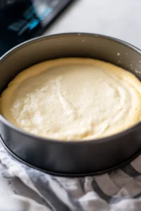 Pour the cheesecake batter into a greased baking dish and place it in the air fryer basket.