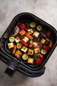 Preheat your air fryer to 200°C and arrange the marinated paneer and vegetables in the basket